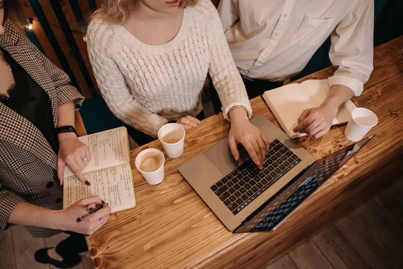 Colleagues around a wooden table with a laptop and notebooks