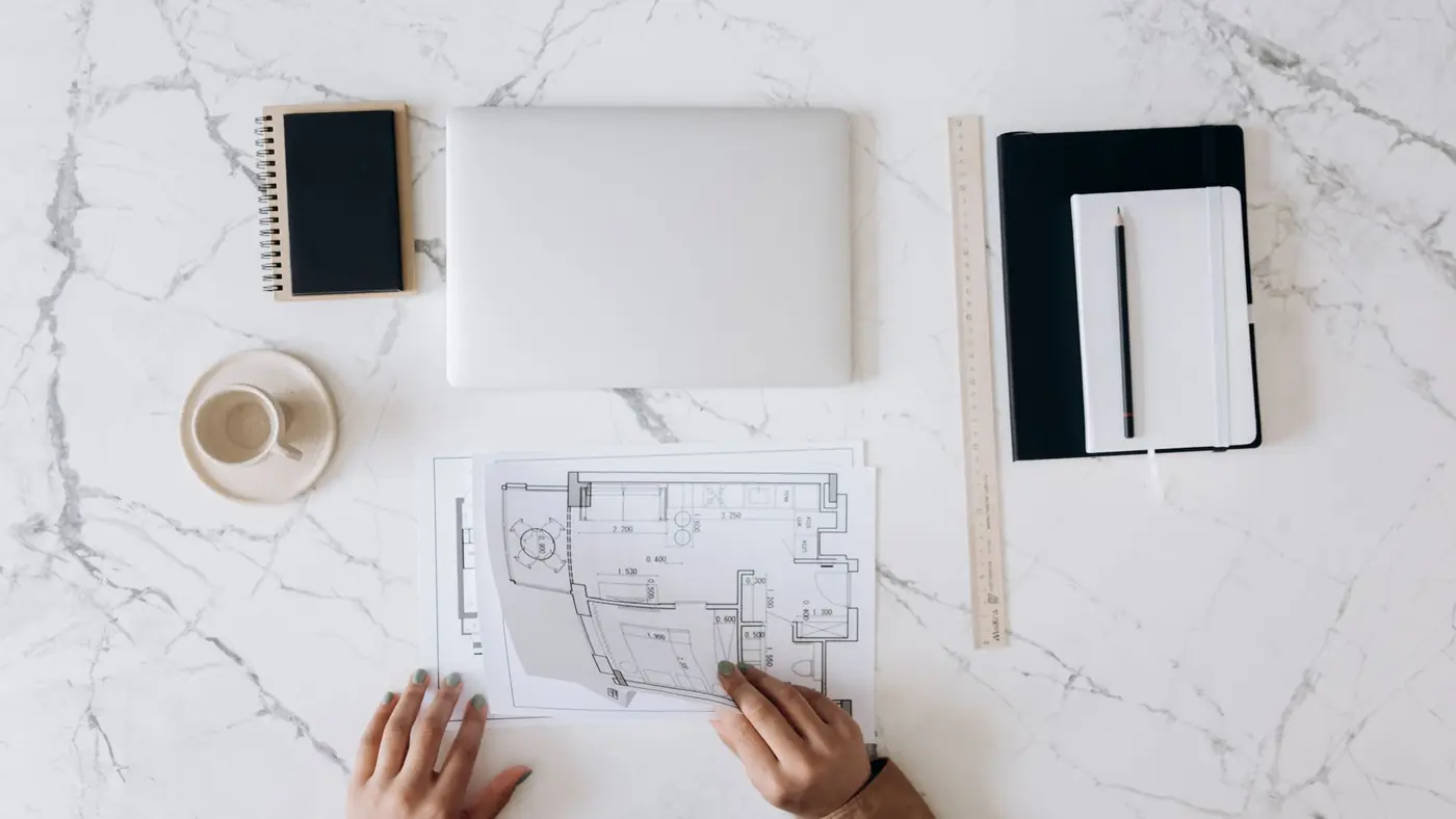 Two people looking over a floor plan on a marble table