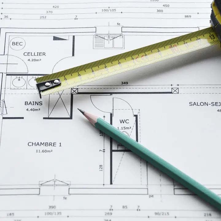 An architectural plan with a tape measure and a pencil